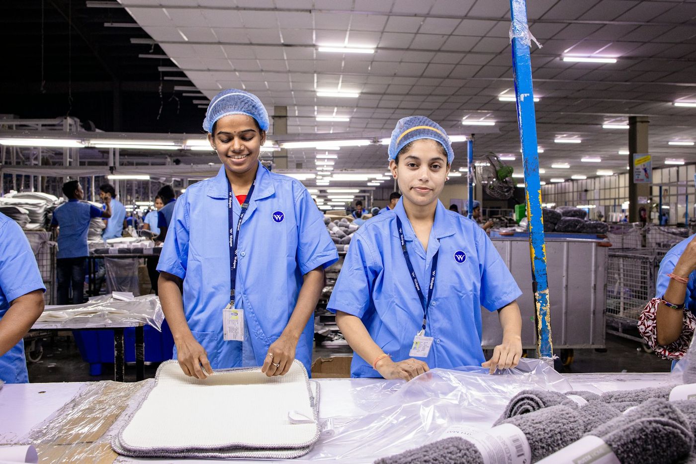 Two young women apprentices in blue uniforms on a shop floor